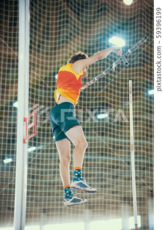 Pole vaulting - man in yellow t shirt is falling after jump with pole Pole vaulting - man in yellow t shirt is falling after jump with pole 59396199