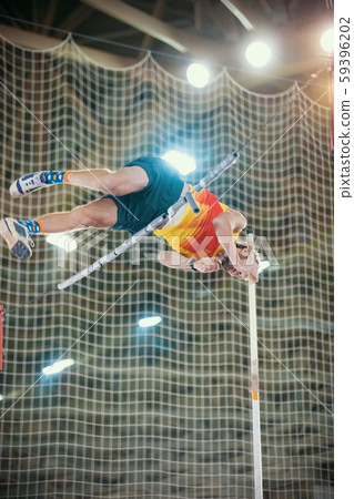 Pole vaulting - man is jumping over the bar in yellow t shirt Pole vaulting - man is jumping over the bar in yellow t shirt 59396202