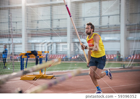 Pole vaulting - man in blue shorts is running with pole in hands Pole vaulting - man in blue shorts is running with pole in hands 59396352