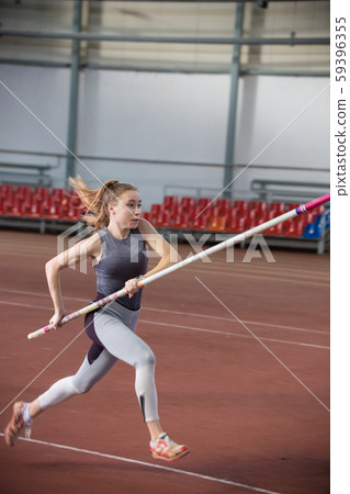 Pole vaulting - woman is running fast in gray leggings and a pole in her hands Pole vaulting - woman is running fast in gray leggings and a pole in her hands 59396355