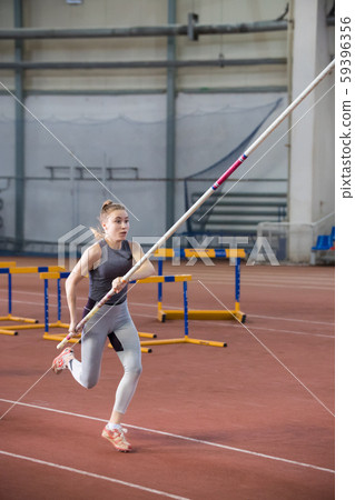 Pole vaulting - pretty woman is running with long pole Pole vaulting - pretty woman is running with long pole 59396356