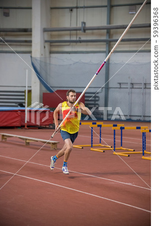 Pole vaulting - man in yellow shirt is running with pole in hands Pole vaulting - man in yellow shirt is running with pole in hands 59396368