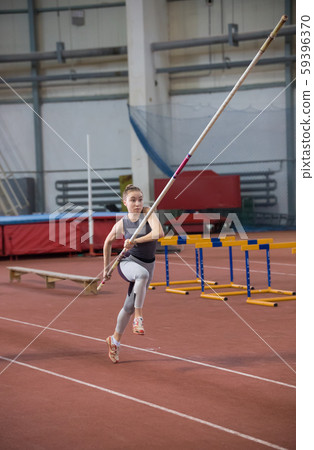 Pole vaulting - young woman is scattering with pole in hands 59396370