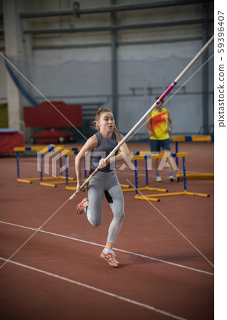 Pole vaulting - woman is running with a long pole in her hands Pole vaulting - woman is running with a long pole in her hands 59396407