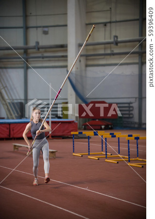 Pole vaulting - woman is going to run with a long pole in her hands Pole vaulting - woman is going to run with a long pole in her hands 59396409