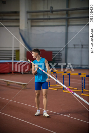 Pole vaulting - a young guy is standing with a pole in hand Pole vaulting - a young guy is standing with a pole in hand 59396426