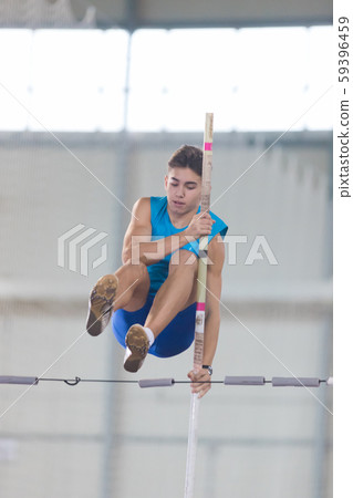 Pole vaulting - guy in a blue t shirt is jumping over the bar Pole vaulting - guy in a blue t shirt is jumping over the bar 59396459