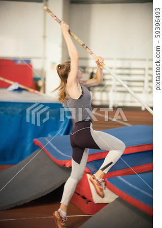 Pole vaulting in the sports stadium - young sportive woman with ponytail in grey leggins about to Pole vaulting in the sports stadium - young sportive woman with ponytail in grey leggins about to 59396493