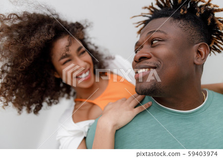 Cheerful Afro American guy giving his girlfriend piggyback Cheerful Afro American guy giving his girlfriend piggyback 59403974