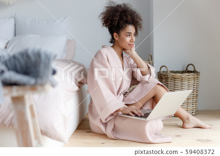 Beautiful Afro American woman using laptop at home Beautiful Afro American woman using laptop at home 59408372
