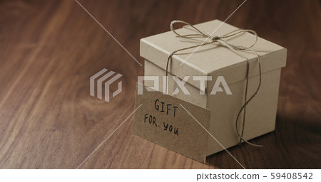 gift for you card next to brown paper gift box on walnut table gift for you card next to brown paper gift box on walnut table 59408542