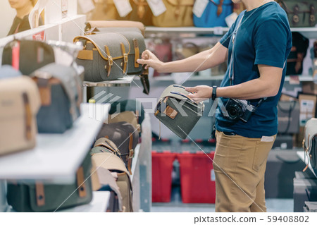 Male photographer choose camera bag that is suitable for the size of the camera used in photoghaphic store. 59408802