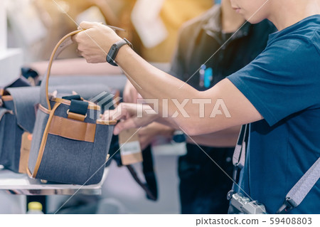 Male photographer choose camera bag that is suitable for the size of the camera used in photoghaphic store. 59408803