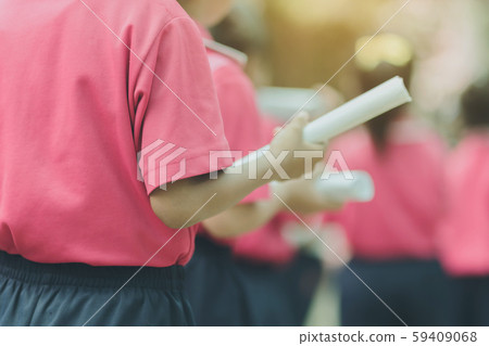 Back view of little girls use paper rolls instead of long cheerleader Baton Sticks for school parade marching practice. 59409068
