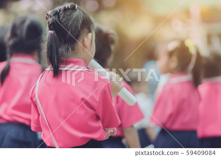 Back view of little girls use paper rolls instead of long cheerleader Baton Sticks for school parade marching practice. 59409084