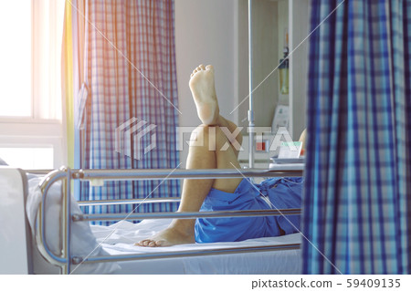 Elderly male patient relaxing on bed with his legs crossed in a good mood to wait for the time to go home. Selective focus on foot sole. Elderly male patient relaxing on bed with his legs crossed in a good mood to wait for the time to go home. Selective focus on foot sole. 59409135