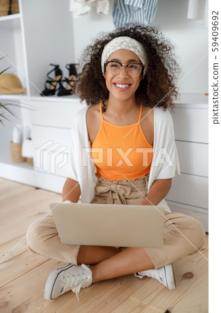 Cheerful Afro American girl with laptop sitting on the floor Cheerful Afro American girl with laptop sitting on the floor 59409692