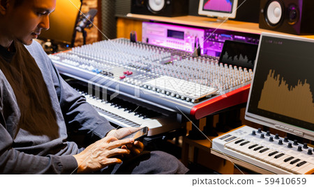 sound engineer listening music, surfing internet and playing social media on smartphone in studio 59410659