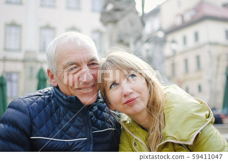 Handsome elderly man is embracing his young blonde wife spending time together outdoors in the Handsome elderly man is embracing his young blonde wife spending time together outdoors in the 59411047