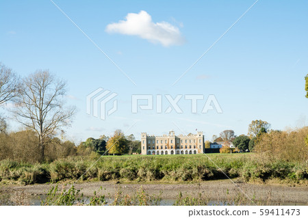 Park and historic stone building with trees and open lawns under the autumn sky Park and historic stone building with trees and open lawns under the autumn sky 59411473
