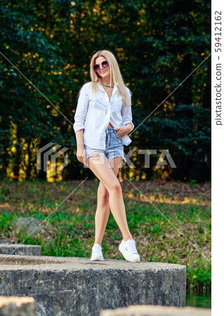 Girl walking in park along stones surrounding Girl walking in park along stones surrounding 59412162