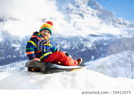 Boy on sled ride. Child sledding. Kid on sledge 59413075