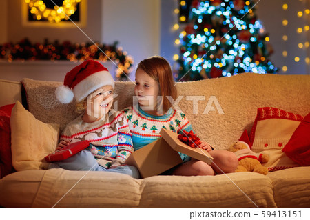 Child at Christmas tree. Kids at fireplace on Xmas Child at Christmas tree. Kids at fireplace on Xmas 59413151