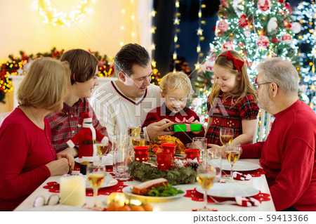 Family with kids having Christmas dinner at tree Family with kids having Christmas dinner at tree 59413366