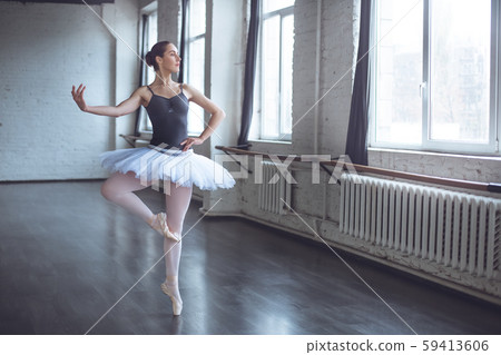 Young ballet dancer practice movement looking out the window in studio active lifestyle Young ballet dancer practice movement looking out the window in studio active lifestyle 59413606