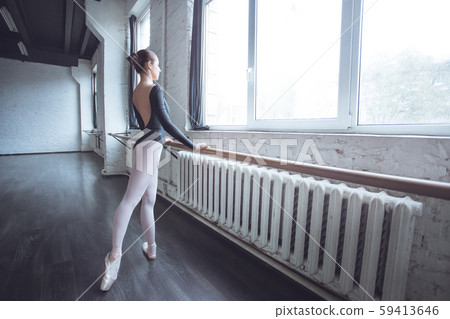 Young ballet dancer practice movement looking out the window in studio active lifestyle Young ballet dancer practice movement looking out the window in studio active lifestyle 59413646