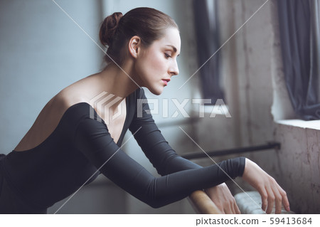 Young ballet dancer leaning on crossbar in studio active lifestyle Young ballet dancer leaning on crossbar in studio active lifestyle 59413684