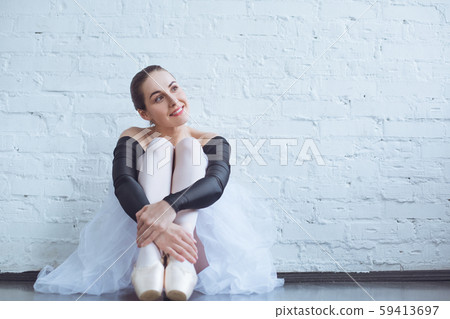 Young ballet dancer sitting leaning white wall in studio dreaming active lifestyle 59413697