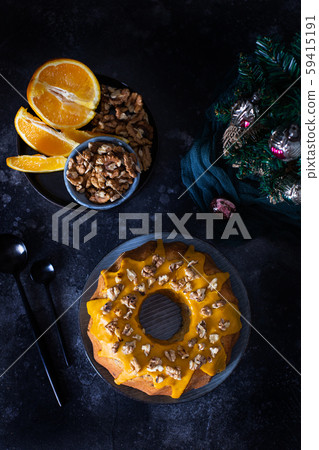 Bundt cake, orange cake with walnuts and yellow sugar icing with turmeric spice. Dark background. View from above Bundt cake, orange cake with walnuts and yellow sugar icing with turmeric spice. Dark background. View from above 59415191