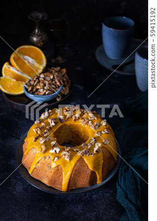 Bundt cake, orange cake with walnuts and yellow sugar icing with turmeric spice. Dark background Bundt cake, orange cake with walnuts and yellow sugar icing with turmeric spice. Dark background 59415192