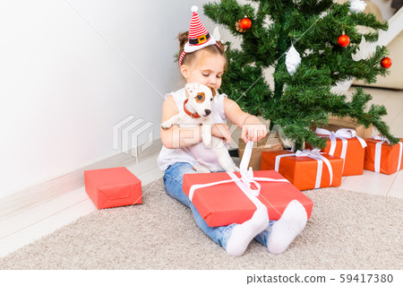 Christmas, pets and holidays concept - Child in santa hat with a jack russell terrier puppy 59417380