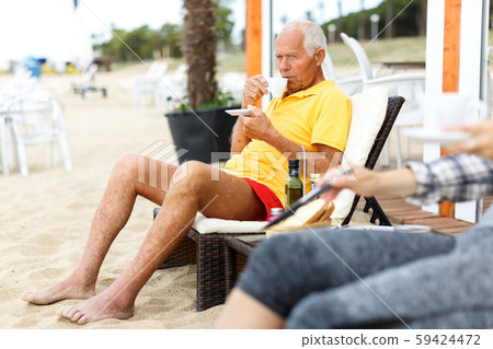 Lucky mature man sitting with cup of hot drink Lucky mature man sitting with cup of hot drink 59424472