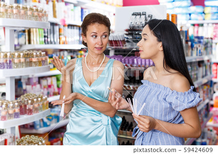 Women customers smelling perfume testers in cosmetic shop Women customers smelling perfume testers in cosmetic shop 59424609