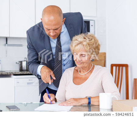 Mature woman and agent fills in documents Mature woman and agent fills in documents 59424651