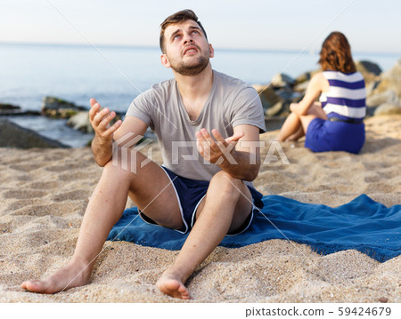 Man sitting with displeasure on the beach Man sitting with displeasure on the beach 59424679