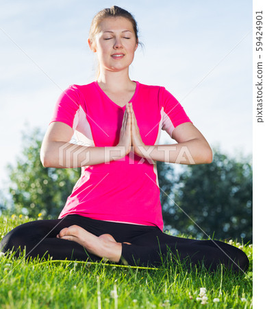 Young girl in pink T-shirt is sitting and meditating Young girl in pink T-shirt is sitting and meditating 59424901