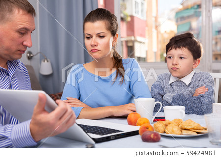 Man with laptop explaining to worried wife and son 59424981