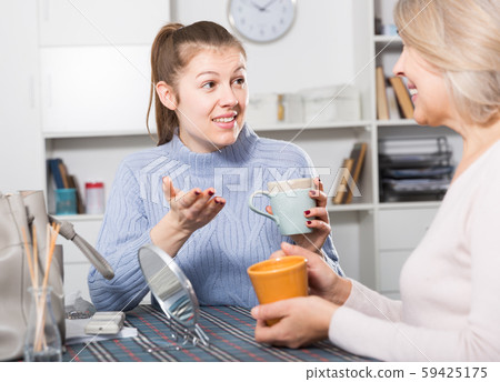Mature mom talks to adult daughter at the table. Tea party Mature mom talks to adult daughter at the table. Tea party 59425175