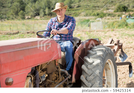 Positive man working on farm tractor 59425314