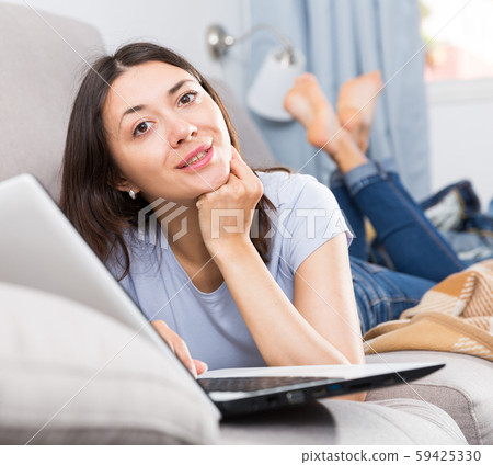 Young woman relaxing on sofa and using laptop at home Young woman relaxing on sofa and using laptop at home 59425330