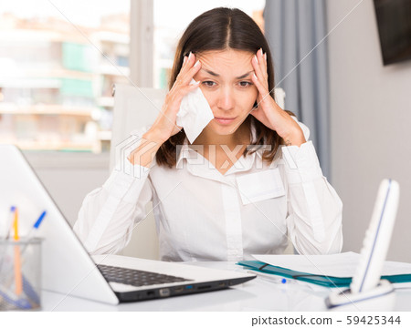 Upset woman crying and holding napkin at laptop at the office 59425344