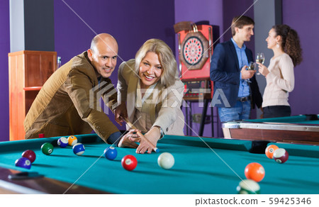 Relaxed people playing billiard and darts Relaxed people playing billiard and darts 59425346