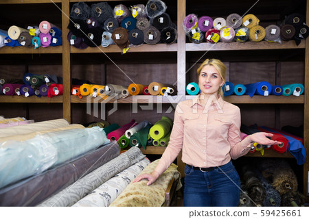 Female seller of fabric shop showing textiles Female seller of fabric shop showing textiles 59425661