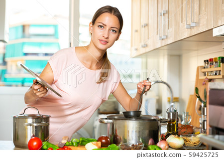 Housewife cooking soup and using laptop 59425725