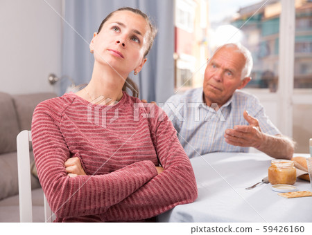 Portrait of upset young woman sitting after quarrel with father Portrait of upset young woman sitting after quarrel with father 59426160