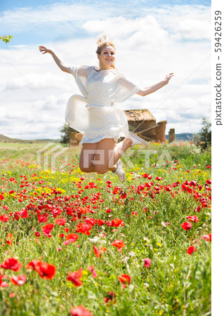 Adult female jumping in poppy field 59426259